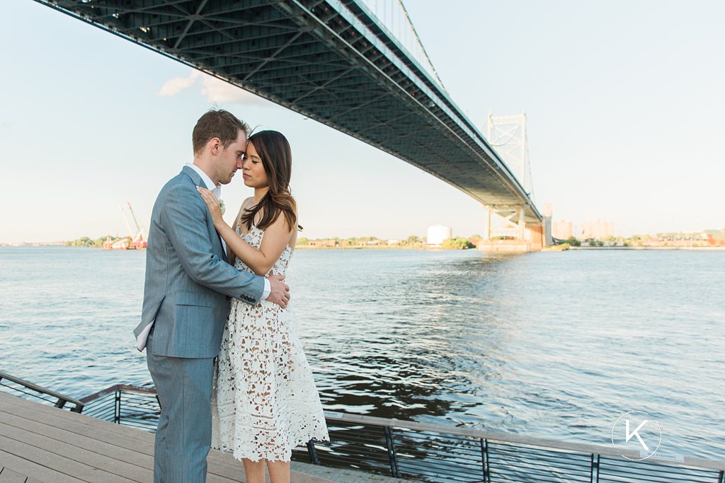 Couple hugging in front of Benjamin Franklin Bridge